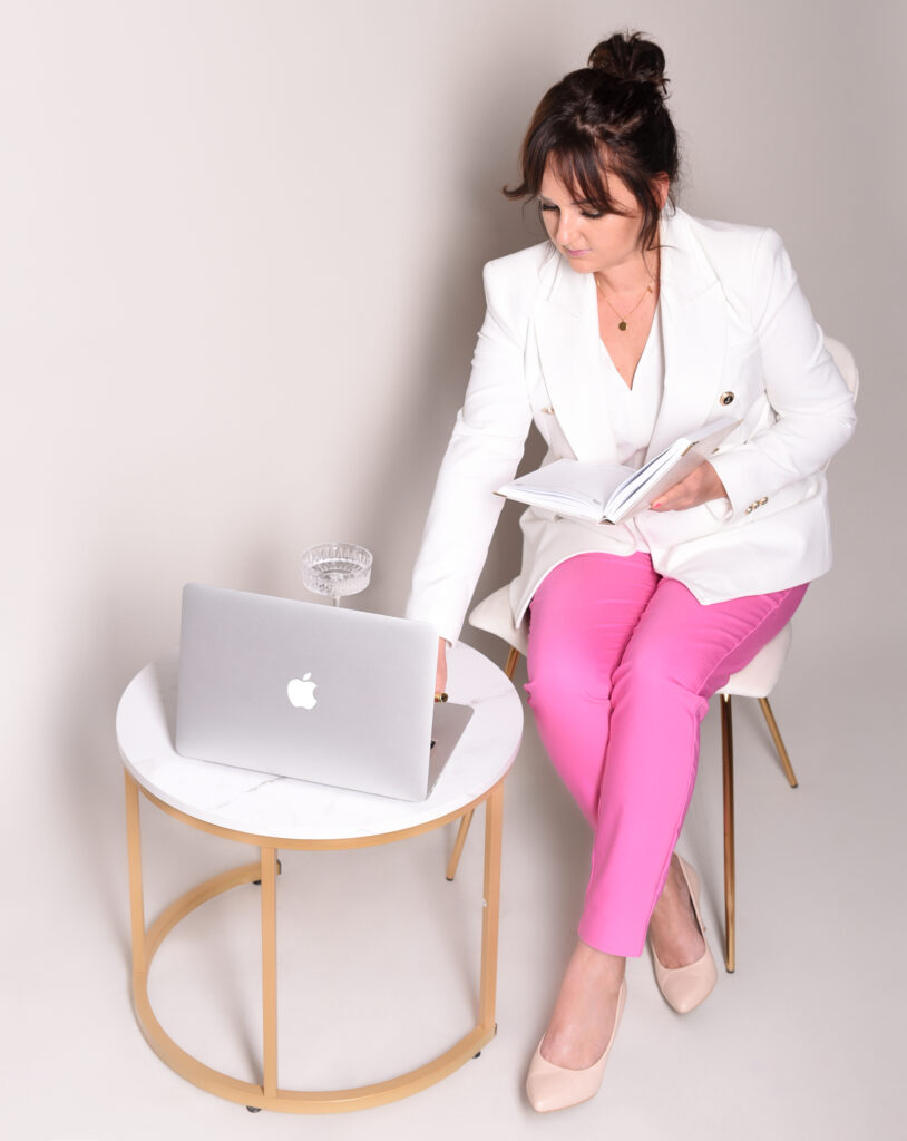 Kobieta w białym żakiecie przy laptopie.