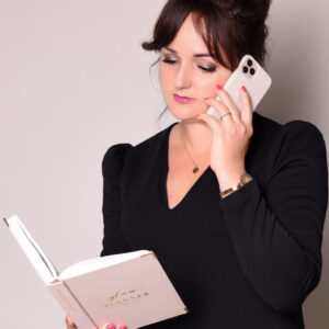 Kobieta trzyma książkę i telefon.